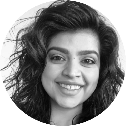 Black-and-white circular headshot of a smiling woman with long wavy dark hair, close-up portrait style.